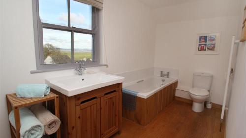 uma casa de banho com um lavatório, uma banheira e um WC. em Orchard Cottage, Landimore em Cheriton