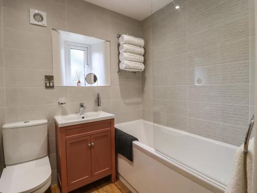 a bathroom with a toilet and a tub and a sink at 1 The Old Chapel in Otley