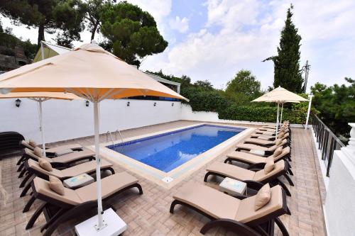 a pool with chairs and umbrellas next to a swimming pool at Noya Köşk Otel in Adalar