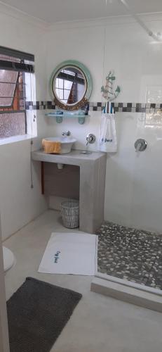 een badkamer met een wastafel en een spiegel bij Cozy Guest in Graskop