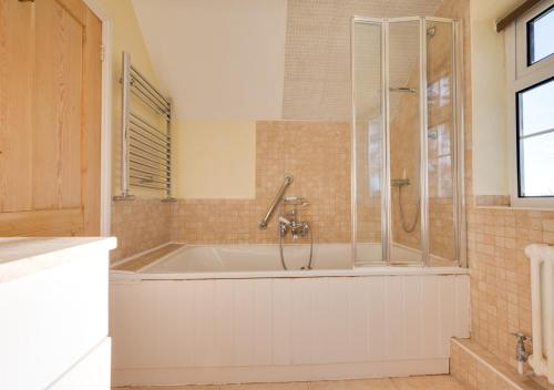 a bathroom with a bath tub with a shower at St Benets in Ludham