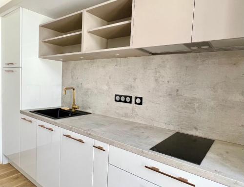 a kitchen with white cabinets and a sink at Appart'hôtel Les Célestins in Vals-les-Bains