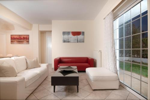 a living room with a white couch and a red chair at SK-George Apartments by the Sea and Airport in Porto Rafti