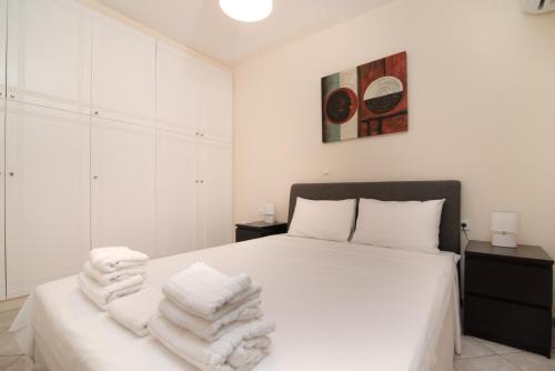 a bedroom with a white bed with towels on it at SK-George Apartments by the Sea and Airport in Porto Rafti