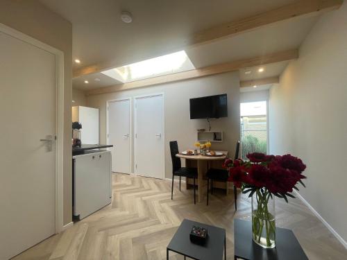 a living room with a kitchen and a table with flowers at Strandhuis aan zee in Noordwijk