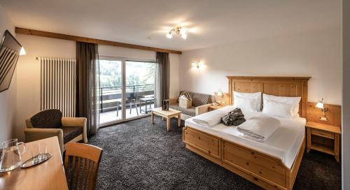 Habitación de hotel con cama grande y escritorio. en Hotel Schmung en Alpe di Siusi