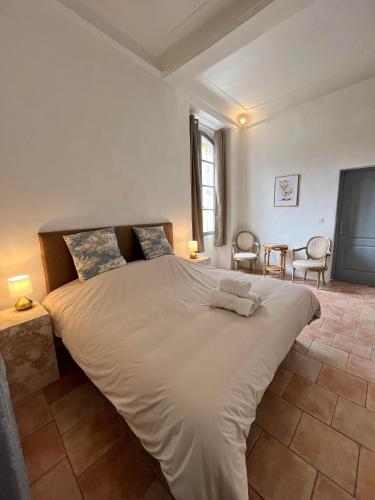 a large white bed in a room with two chairs at La Tour de Pezene in Anduze