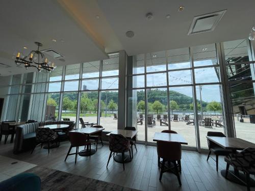 a restaurant with tables and chairs and a large window at The Landing Hotel at Rivers Casino Pittsburgh in Pittsburgh