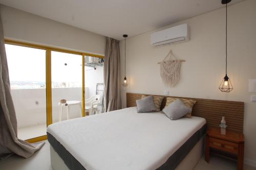 a bedroom with a white bed and a balcony at Casa3_Praia_Beach_House in Portimão
