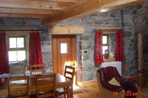 ein Esszimmer mit einem Tisch und einer Steinmauer in der Unterkunft Traditional Stone Cottage 300 years+ in Galway