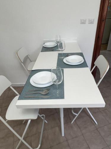 ナポリにあるCasa nel cuore di Napoliの白いテーブル(皿、ワイングラス付)