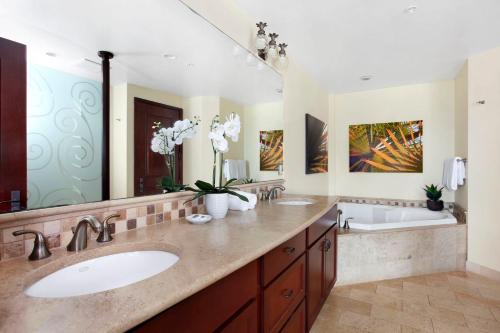 a bathroom with two sinks and a large mirror at Waipouli Beach Resort Penthouse Beautiful Oceanview Aloha! AC Pool in Kapaa