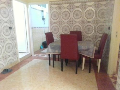 a dining room with a table and red chairs at Apartments in Attaouia Wonderful in Attaouiya ech Chaïbiya