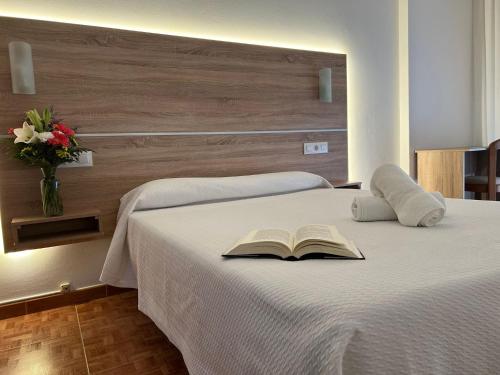 Un dormitorio con una cama con un libro. en Hotel Argibay, en O Grove