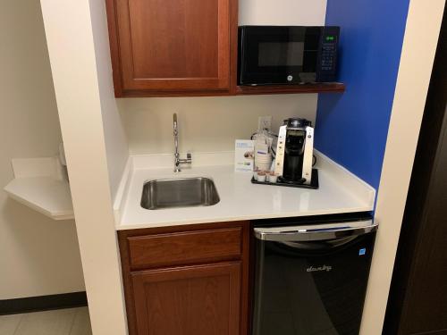 eine kleine Küche mit einer Spüle und einer Mikrowelle in der Unterkunft Holiday Inn Express Hotel & Suites Minneapolis-Downtown Convention Center, an IHG Hotel in Minneapolis