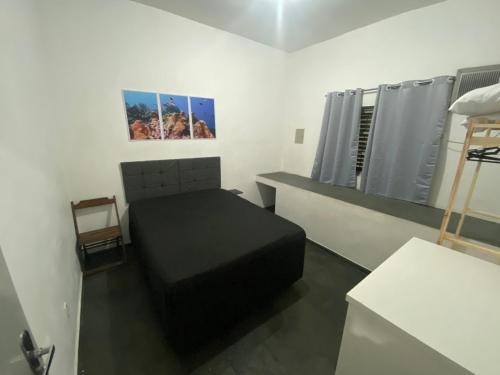 Dormitorio pequeño con cama negra y espejo en Casa 2 dorm, otima localizacao, Wi-Fi, Gar, pet, en Campinas