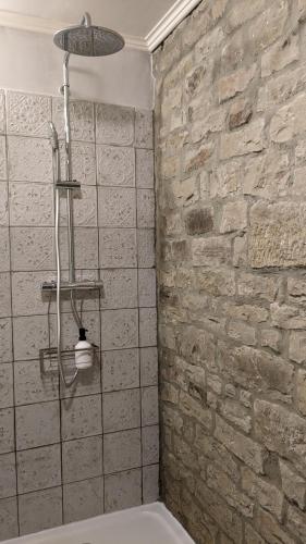 a shower in a bathroom with a stone wall at Manoir La Cerise in Fougerolles