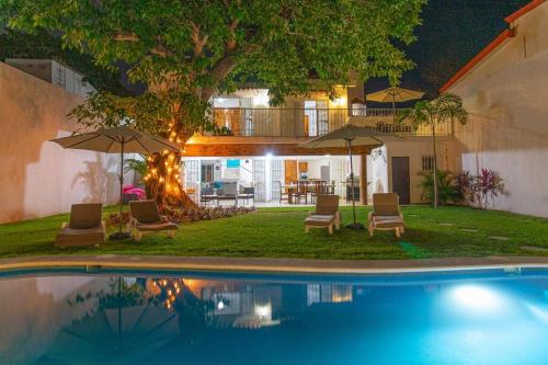 a pool with chairs and umbrellas next to a house at Casa Ines Alberca Privada in Puerto Vallarta