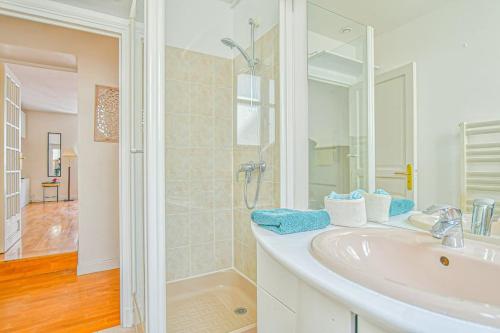 ein weißes Bad mit einem Waschbecken und einer Dusche in der Unterkunft Bright Parisian Flat - Marais in Paris
