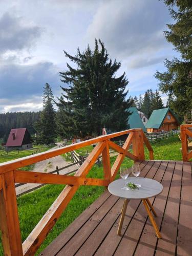 a wooden deck with a table and wine glasses on it at Aleksa’s chalet in Žabljak