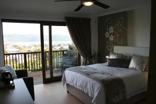 a bedroom with a bed and a balcony with a view at Fijnbos Guesthouse in Knysna