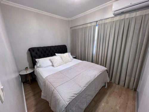 a small bedroom with a bed and a window at Aconchegante Apartamento decorado e mobiliado in Cascavel
