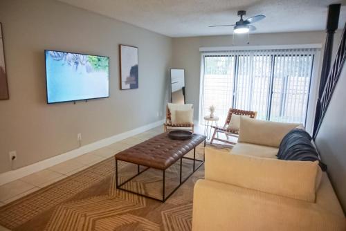 a living room with a couch and a tv on a wall at USF & Busch Gardens Townhome Stay in Tampa