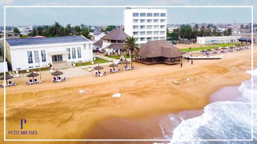 a view of a beach with chairs and a building at Hotel Petit Brussel in Lomé