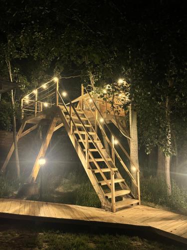 a wooden bridge with lights on it at night at Przystanek Czasu - domek kopułowy in Sułów