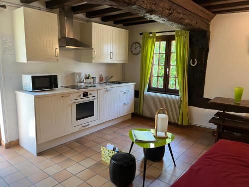 une cuisine avec des armoires blanches, une table et une fenêtre dans l'établissement Le Domaine des Tostes, à Bonneville-la-Louvet