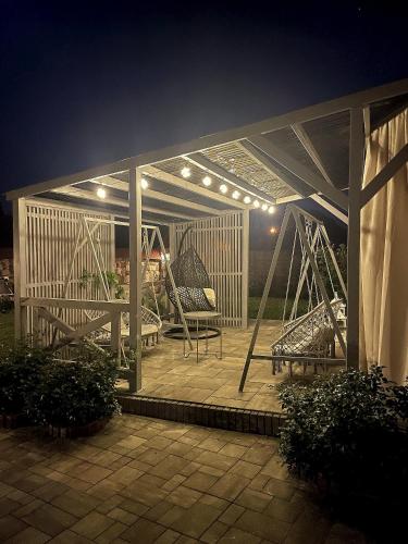 a pavilion with a table and chairs on a patio at night at Przystanek Czasu - domek kopułowy in Sułów