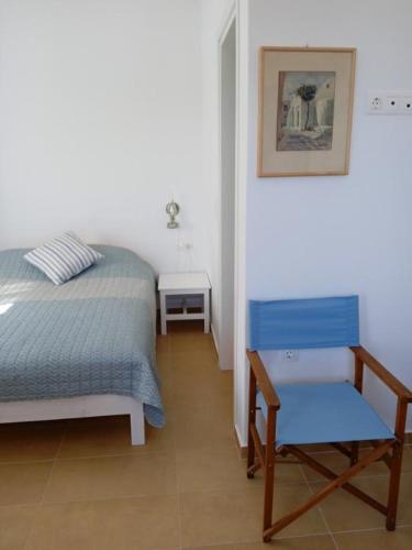 a bedroom with a bed and a blue chair at Το Κυμα . in Livadi Astypalaias