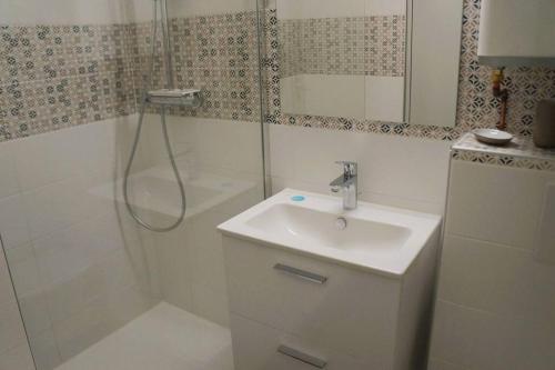 une salle de bain blanche avec un lavabo et une douche dans l'établissement Studio climatisé et spacieux situé près des Parcs, à Vichy