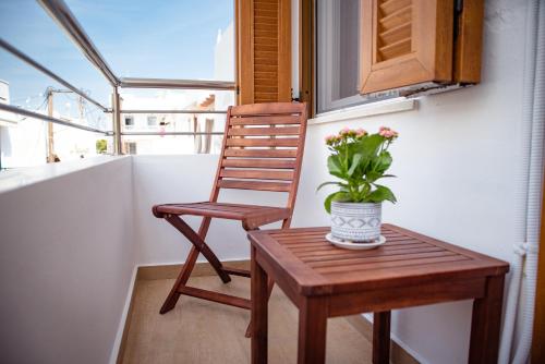 a chair and a table with a vase of flowers on a balcony at Anasasmos House in Naxos Chora