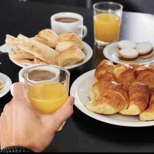 una persona sosteniendo un vaso de jugo de naranja junto a platos de pasteles en Aguas de Oro, en Villa Gesell