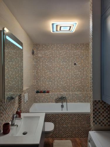 uma casa de banho com uma banheira e um lavatório em Bougainvillea Apartman em Sfântu Gheorghe