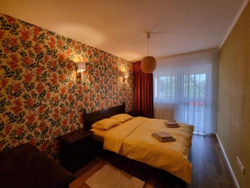 um quarto com uma cama com papel de parede floral em Bougainvillea Apartman em Sfântu Gheorghe