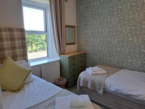 a small bedroom with two beds and a window at Bogrie Cottage in Canonbie