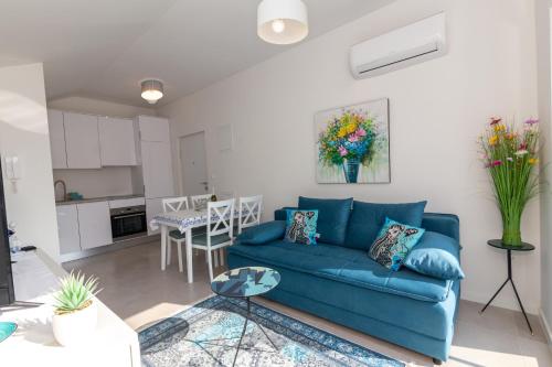 Una sala de estar con un sofá azul y una cocina. en Apartman SAFIR Živogošće, en Živogošće