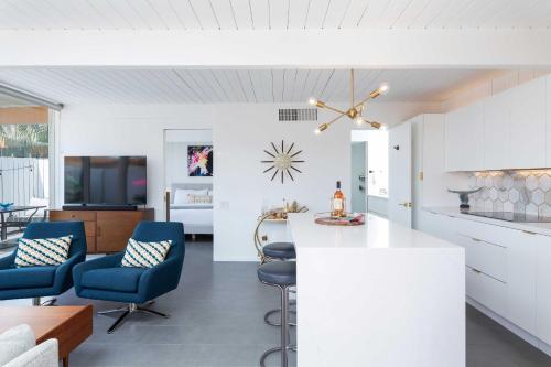 a kitchen and living room with white cabinets and blue chairs at Modern Bungalow in Historic Ocotillo Lodge! in Palm Springs