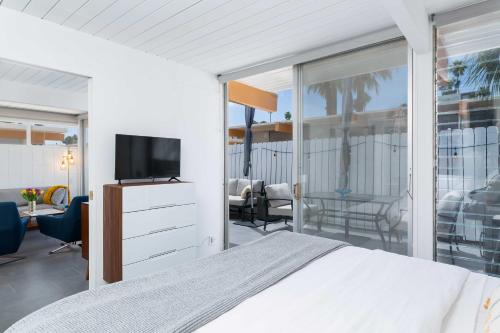 a bedroom with a bed and a tv and a balcony at Modern Bungalow in Historic Ocotillo Lodge! in Palm Springs