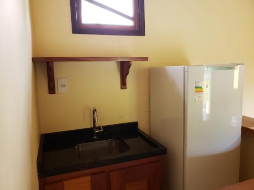 a kitchen with a sink and a refrigerator at Pousada Pratigi in Ituberá