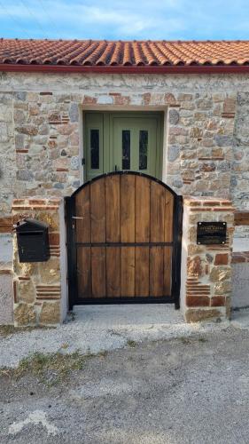 a house with a wooden gate in front of it at Stone House - Πέτρινο Σαλέ in Alíartos