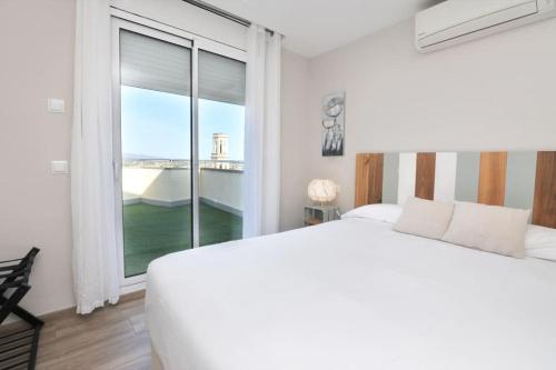 a bedroom with a white bed and a large window at Atico frente al museo Dali in Figueres