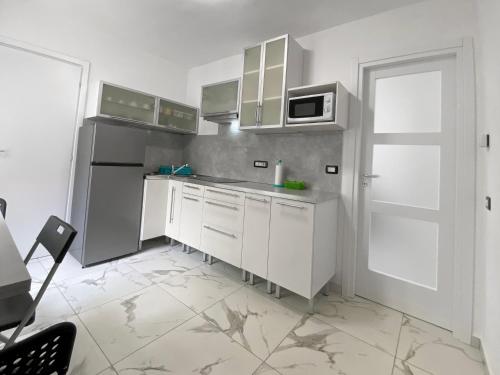 uma cozinha com armários brancos e um frigorífico branco em Accogliente appartamento em Ballabio