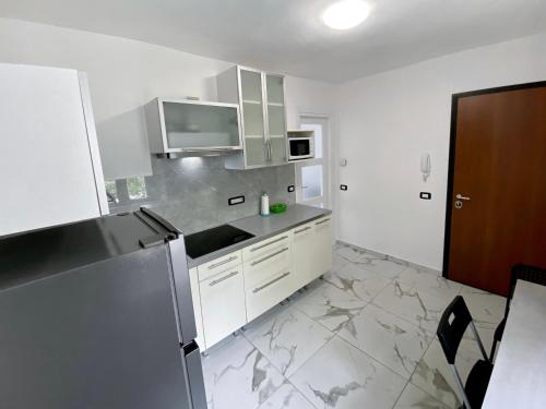 uma cozinha com armários brancos e um frigorífico de aço inoxidável em Accogliente appartamento em Ballabio