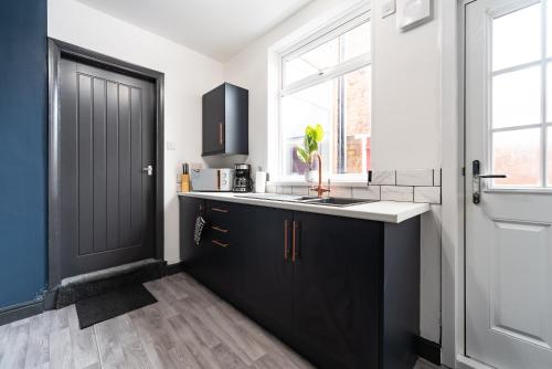 une cuisine avec des armoires noires et une porte noire dans l'établissement Ephphatha 4 Beds Central A63 3 Bedrms Free Wifi, à Hull