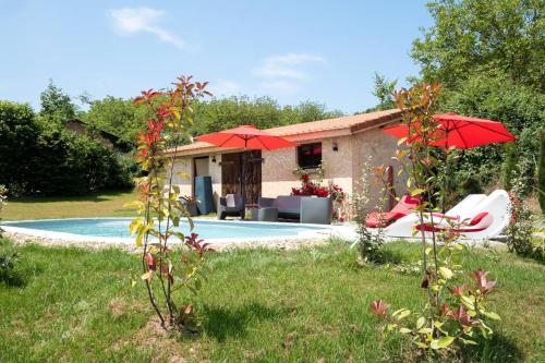 une maison avec une piscine et des parasols rouges dans l'établissement COMBE JOLIE Clim, Piscine & Jacuzzi, à Saint-Vincent-de-Cosse