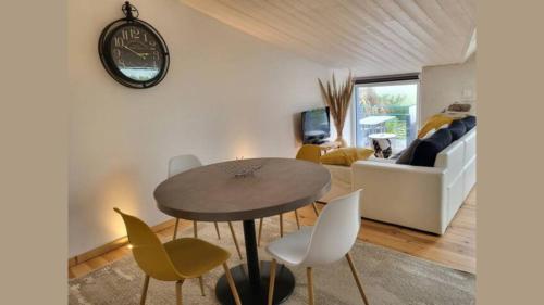 ein Wohnzimmer mit einem Tisch, Stühlen und einem Sofa in der Unterkunft Gîte de Charme avec vue Mer in Saint-Jean-Trolimon