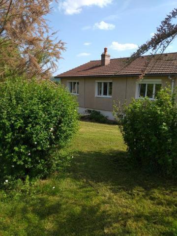 une maison dans une cour avec des buissons devant elle dans l'établissement La maison d'Ormancey, à Mont-Saint-Jean